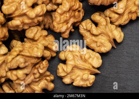 Walnuts. Walnut kernels on dark black stone background. Top view, flat lay Stock Photo