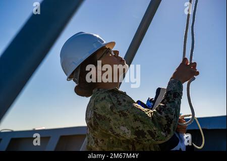 PERTH, Australia (April 13, 2022) – Quartermaster Seaman Luvima Andrade, from Miami, raises the Union Jack flag aboard the Emory S. Land-class submarine tender USS Frank Cable (AS 40) as the ship moors pier side at Royal Australian Navy base HMAS Stirling, Australia. Frank Cable is currently on patrol conducting expeditionary maintenance and logistics in support of national security in the U.S. 7th Fleet area of operations. Stock Photo