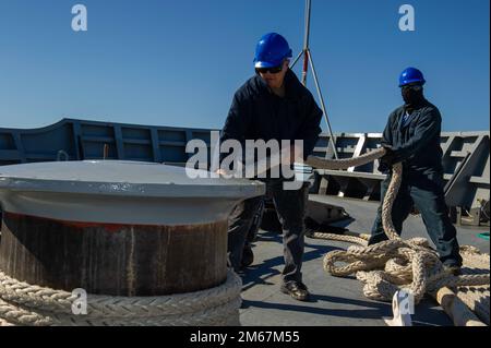 PERTH, Australia (April 13, 2022) Civilian service mariners from Guam, Edgard Leano, left, and Erick Guico, right, wrap lines around the capstan aboard Emory S. Land-class submarine tender USS Frank Cable (AS 40) as the ship moors pier side at Royal Australian Navy base HMAS Stirling, Australia. Frank Cable is currently on patrol conducting expeditionary maintenance and logistics in support of national security in the U.S. 7th Fleet area of operations. Stock Photo