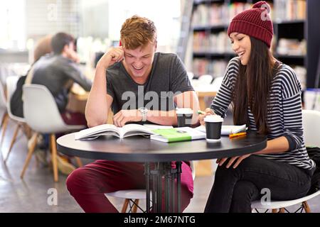 Doing some exam prep with a friend. two college students studying together at the library. Stock Photo