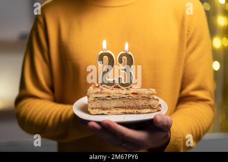 Cake with the number 23 lighted candles in men hands. 23th birthday Stock Photo