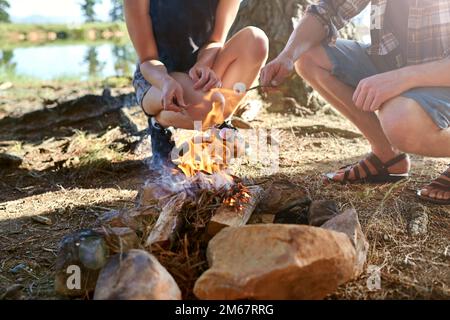 Enjoying a great campfire tradition. two campers roasting marshmallows over a campfire. Stock Photo