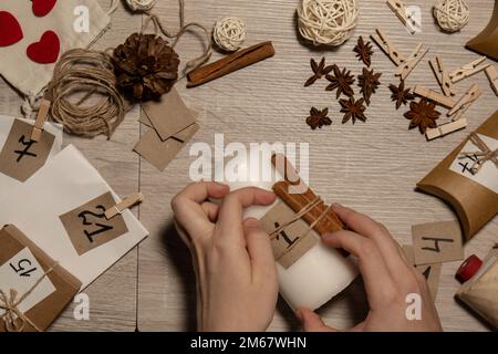 Unrecognizable young woman paint numbers on candles. Female making homemade advent calendar Made with your own hands step by step DIY crafts do it yourself. Preparation to christmas concept. Seasonal activities for children family winter holidays. Eco friendly presents gifts. open the package every day Stock Photo