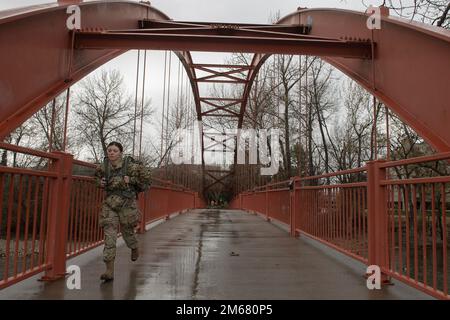 Boise State University Army ROTC Cadet Melanie Reese crosses the red bridge over the Boise River on her way to the turn-around point at Barber Park.    The Boise State University ROTC Cadets nearing the end of the semester showed no let up in their schedules. In mid-April, two groups of cadets took a scenic ruck march along the Boise Green Belt Trail system. Group one completed a 12-mile ruck march while group 2 completed an 8-mile march.    Seeking fitness of another kind, the cadets attended a briefing from Mr. Cody Rome, a 2012 graduate of the Naval Academy at Annapolis, on managing their f Stock Photo