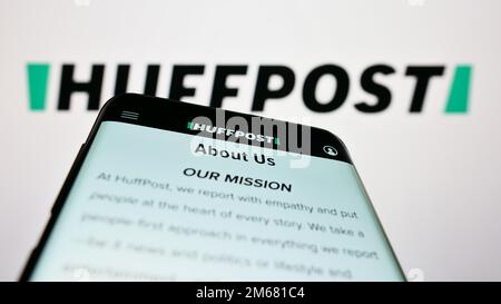 Smartphone with website of US news company HuffPost on screen in front of business logo. Focus on top-left of phone display. Stock Photo