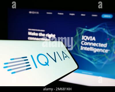 Smartphone with logo of US health technology company IQVIA Holdings Inc. on screen in front of website. Focus on center-right of phone display. Stock Photo