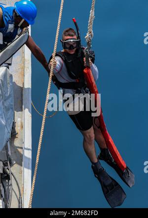 GULF OF OMAN (April 15, 2022) Gunner’s Mate 3rd Class Christopher Hart gets lowered into the water during a search and rescue drill aboard the guided-missile destroyer USS Gridley (DDG 101) in the Gulf of Oman, April 15. Gridley is deployed to the U.S. 5th Fleet area of operations to help ensure maritime security in the Middle East region. Stock Photo