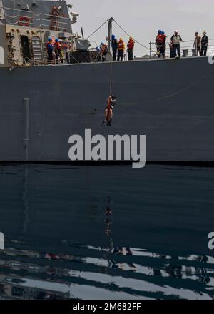 GULF OF OMAN (April 15, 2022) Gunner’s Mate 3rd Class Christopher Hart gets lowered into the water during a search and rescue drill aboard the guided-missile destroyer USS Gridley (DDG 101) in the Gulf of Oman, April 15. Gridley is deployed to the U.S. 5th Fleet area of operations to help ensure maritime security in the Middle East region. Stock Photo