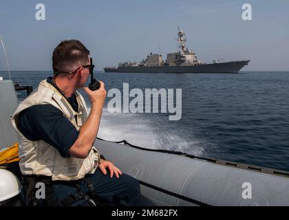 GULF OF OMAN (April 15, 2022) Ensign Trevor North communicates plans for a rigid-hull inflatable boat (RHIB) recovery to personnel aboard the guided-missile destroyer USS Gridley (DDG 101) at the conclusion of a search and rescue drill in the Gulf of Oman, April 15. Gridley is deployed to the U.S. 5th Fleet area of operations to help ensure maritime security in the Middle East region. Stock Photo