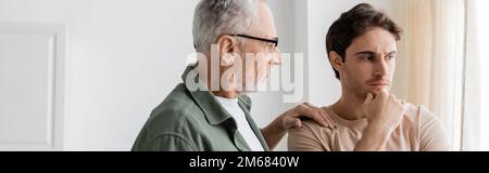 senior man touching shoulder of thoughtful and upset son standing with hand near face, banner,stock image Stock Photo
