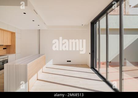 Large bright spacious kitchen with wooden furniture and closed black metal sliding glass doors with access to the terrasse. Modern design of the Stock Photo