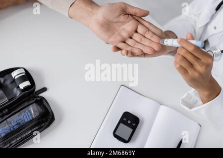 top view of african american doctor taking blood sample of patient with lancet pen,stock image Stock Photo