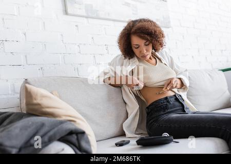 Young african american woman with diabetes doing injection of insulin in belly,stock image Stock Photo