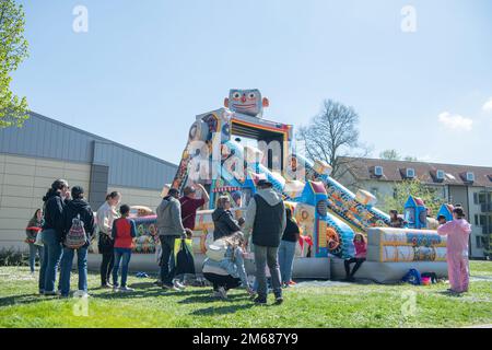 Wiesbaden parents and children stand in line for the inflatable slide at the Kinderfest event April 16, 2022, on Hainerberg Housing Area in Wiesbaden, Hessen, DE. The event featured a myriad of youth activities including face painting, bungy jumping, and carousel riding. Stock Photo