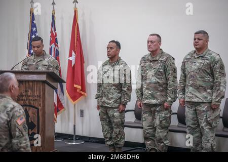 Hawaii Army National Guard (HIARNG) Lt. Col David R. Hatcher, right, incoming commander of the 29th Infantry Brigade Combat Team (IBCT), Brig. Gen. Stephen F. Logan, HIARNG Commander and Col. Jonathan A. Ishikawa, outgoing commander of the 29th IBCT, stand at attention during the opening remarks of the 29th IBCT change of command ceremony at Kalaeloa, Hawaii, Apr. 18, 2022. A change of command ceremony symbolizes the exchange from one command to the next. Stock Photo