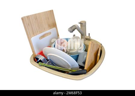 Sink with dirty dishes in the kitchen, isolated on a white background. Plates, cups, cutlery and cutting boards lie in the sink Stock Photo