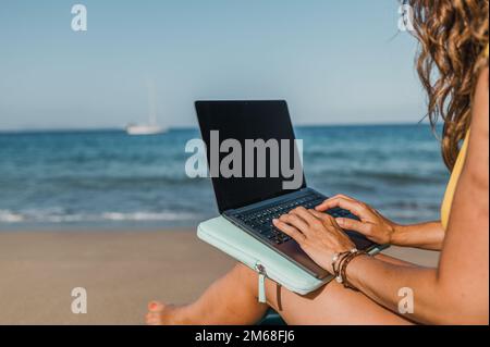 Unrecognizable woman typing on laptop near sea Stock Photo