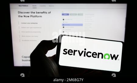 Person holding cellphone with logo of US software company ServiceNow Inc. on screen in front of business webpage. Focus on phone display. Stock Photo