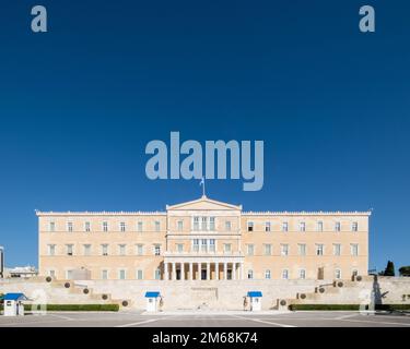 Hellenic Parliament, Athens, Greece, photographed on a bright sunny day with deep blue sky above. A Greek flag flutters on the top, and soldiers of th Stock Photo