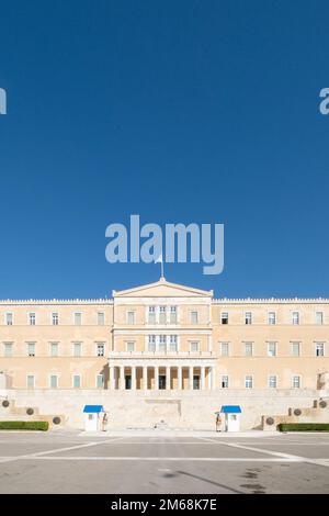 Hellenic Parliament, Athens, Greece, photographed on a bright sunny day with deep blue sky above. A Greek flag flutters on the top, and soldiers of th Stock Photo