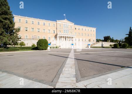 Hellenic Parliament, Athens, Greece, photographed on a bright sunny day with deep blue sky above. A Greek flag flutters on the top, and soldiers of th Stock Photo