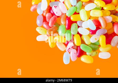 Jelly beans sweets candy piled on an orange background. High sugar unhealthy food concept Stock Photo