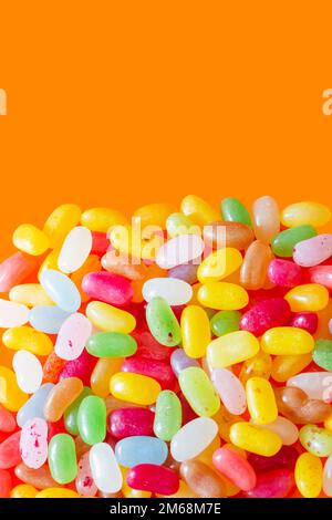 Jelly beans sweets candy piled on an orange background. High sugar unhealthy food concept Stock Photo