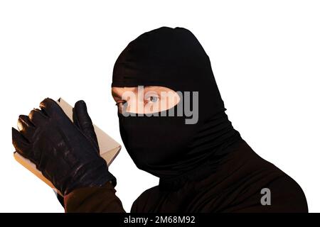 A thief in a black mask steals a box of goods in a warehouse in the dark, isolated on a white background. Concept of problems with theft of goods and Stock Photo