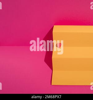 Yellow paper podium with red heart on magenta background. Minimal love or valentine concept. Stock Photo