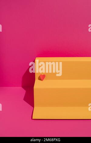 Yellow paper podium with red heart on magenta background. Minimal love or valentine concept. Stock Photo