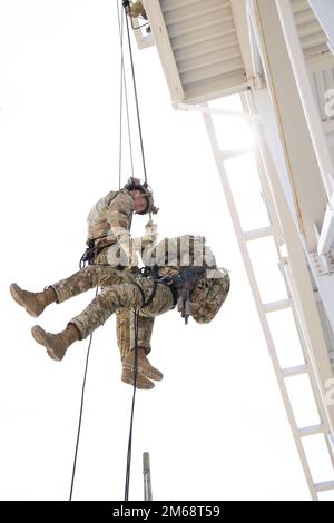 A Green Beret with 10th Special Forces Group (Airborne) assists in recovering a simulated hung rappeler from a tower at Fort Carson, Colorado, April 19, 2022. Special Forces Operators use rappelling to insert into areas from elevated positions when time or surprise is required by the mission. Stock Photo