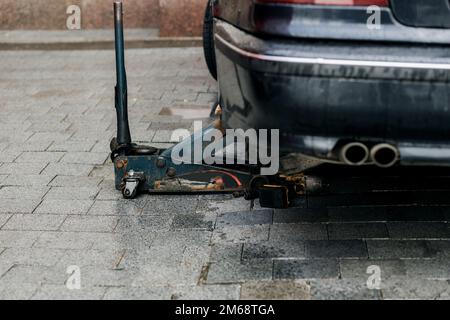 wheel removed, lifted by hydraulic jack, car repair on the roadside Stock Photo