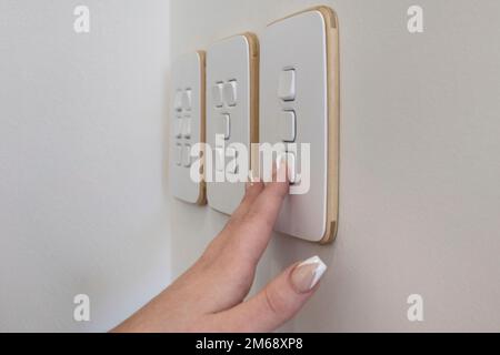 Manicured hand turning light switch on or off Stock Photo