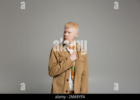 bearded albino man in stylish shirt jacket and silk scarf posing isolated on grey,stock image Stock Photo