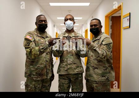 Lt. Gen. R. Scott Dingle, left, surgeon general of the Army and Medical Command commanding general, and MEDCOM Command Sgt. Maj. Diamond D. Hough, right, present a coin at SHAPE Healthcare Facility to Lt. Col. Simeon Smith, chief of public health for the SHAPE and Brussels healthcare facilities, April 20, 2022 at Casteau, Belgium. Stock Photo