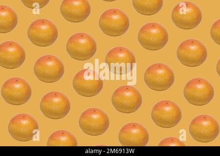 Pattern made of whole ripe ruby grapefruit on yellow background Stock Photo