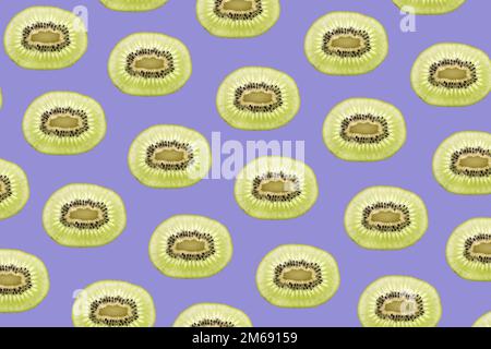 Pattern made of backlit kiwi fruit slices on blue background Stock Photo