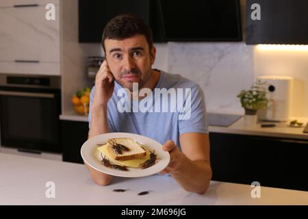Grossed out man finding cockroaches on his sandwich Stock Photo