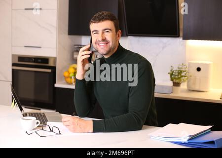 Handsome man calling by phone from home office Stock Photo