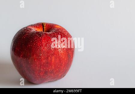 Beautiful close up of red apple on white background with blurred background. Red apple with water droplets on white backdrop. Stock Photo