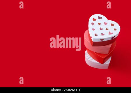 Heart shaped boxes decorated with pink and red hearts on red background Stock Photo
