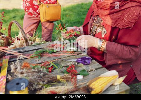 A woman collects a bouquet of dried flowers and red berries Stock Photo