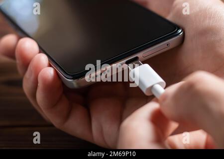 Man hands plugging a charger in a smart phone Stock Photo