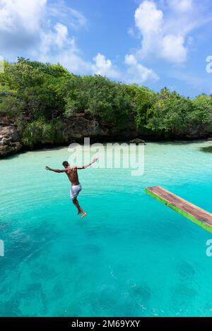 Young local man jumps into Weekuri Lake, an ocean fed lagoon. Stock Photo