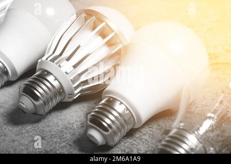Incandescent lamp and various LED lamps with e27 base on gray background with light flare Stock Photo