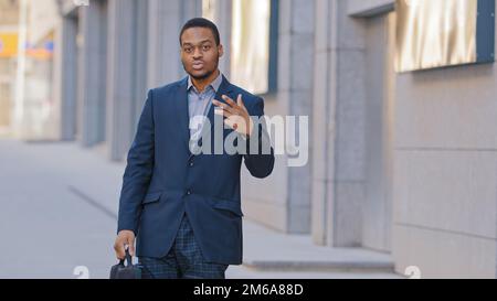 Confident African American serious man employee entrepreneur businessman ethnic male guy worker manager posing funny dancing looking at camera in city Stock Photo