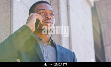 African American man sales manager worker entrepreneur employer lawyer salesman male guy talking mobile phone serious ethnic businessman making Stock Photo