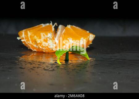 Cut tangerine with splashes of water on a black background Stock Photo