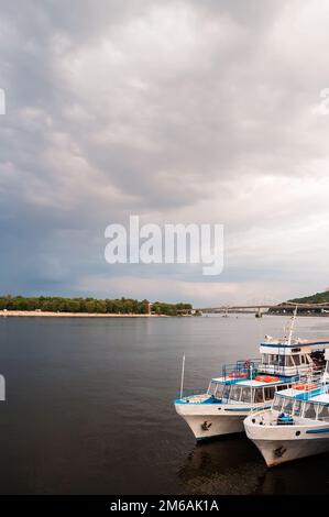 Kyiv, Ukraine. July 19. 2014. View of the Dnieper River with pleasure boats, city beach and pedestrian bridge in the background. Cloudy weather with d Stock Photo