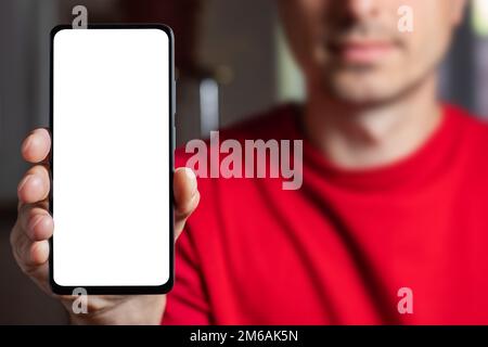 Man demonstrating smartphone with big blank white screen at camera. Man showing copy space for mobile app advertisement. Mockup Stock Photo
